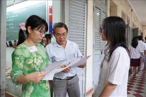 在黎鸿峰高中专校考点，监考干部在进入考室前检查考生信息。