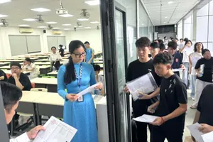 Cán bộ coi thi gọi thí sinh vào phòng thi tại điểm thi Trường ĐH Công nghiệp TPHCM - Ảnh: THANH HÙNG