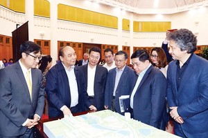 PM Nguyen Xuan Phuc (second from left) and participants examine the model of the National Innovation Centre.(Photo: VNA)