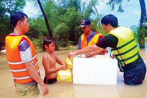 A boy receives food from rescue force in the Mekong Delta (Photo: SGGP)