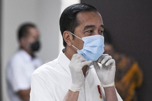 President Joko Widodo adjusts his face mask while visiting COVID-19 patients (Photo: AFP)