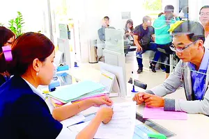 Cán bộ UBND quận 1 hướng dẫn thủ tục hành chính cho người dân.  Ảnh:  VIỆT DŨNG