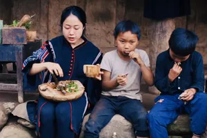 Vương Anh cùng trẻ em bản địa thưởng thức món bồ câu nướng vừa nấu tại Tủa Châu - Điện Biên  (Ảnh cắt từ clip)