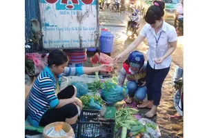 Công nhân tan ca chọn mua rau tại chợ tự phát         trên đường Lê Văn Chí, quận Thủ Đức.  Ảnh: HẢI THU