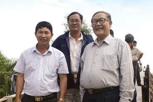 Ông Trịnh Văn Y (bên phải) đi kiểm tra một cây cầu sắp hoàn thành