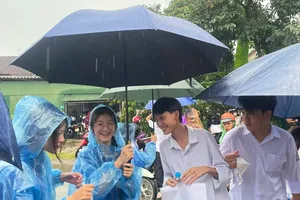 Đoàn viên, thanh niên dùng ô dù che mưa đưa đón thí sinh vào điểm thi 