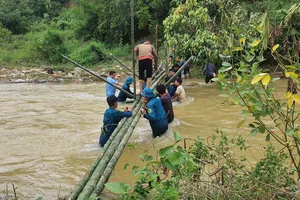 Các lực lượng chức năng và người dân xã Yên Na làm cầu tạm qua khe Chà Hạ vào hai bản cô lập 