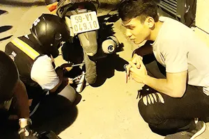 Nhóm thiện nguyện đang vá xe giúp một đôi bạn  trên đường Phổ Quang (ảnh chụp lúc 22 giờ 30 tối 20-8-2017)