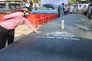 Người dân tham quan túi chứa nước ngọt do các doanh nghiệp  giới thiệu để ứng phó với xâm nhập mặn. Ảnh: HỮU HIỆP