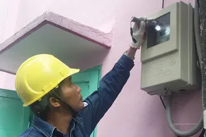 Nhân viên ngành điện kiểm tra việc lắp đặt  công tơ đo đếm từ xa mới tại nhà dân