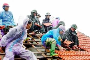 Lực lượng chức năng giúp người dân ở xã Thịnh Lộc (huyện Lộc Hà, tỉnh Hà Tĩnh) lợp lại mái nhà sau mưa bão. Ảnh: DƯƠNG QUANG