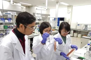 Nguyễn Trường Thịnh (bìa trái) trong áo blouse ở nơi làm việc.  Nguồn: vnuhcm.edu.vn