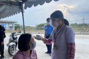 Kiểm tra thân nhiệt cho người đi đường tại chốt kiểm soát dịch trên Quốc lộ 1K phường Hóa An, TP Biên Hòa