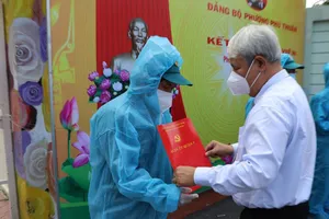 Bí thư Quận ủy quận 7 Võ Khắc Thái trao quyết định kết nạp Đảng cho đảng viên mới tại điểm cách ly  ở Trường Mầm non Phú Thuận. Ảnh: GIA BẢO