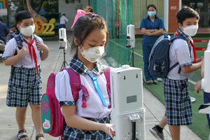 Học sinh Trường Tiểu học Lê Đức Thọ (quận Gò Vấp, TPHCM) vệ sinh tay trước sự giám sát của giáo viên khi vào cổng trường. Ảnh:  HOÀNG HÙNG