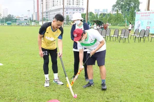 Huấn luyện viên hướng dẫn các kỹ thuật cơ bản  trong bộ môn hockey cho các trẻ đặc biệt và phụ huynh. Ảnh: NGUYỄN ANH