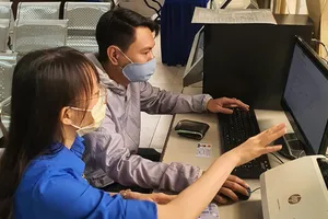 Công chức UBND quận Bình Thạnh hướng dẫn người dân  thực hiện đăng ký hồ sơ qua mạng. Ảnh: Thái Phương