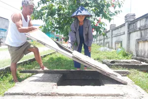 Người dân ở khu tái định cư thôn 1, 2 Tân Phúc Thành  dùng tôn che tạm các hố ga sâu