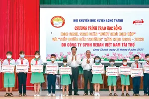 Ông Dương Minh Dũng - Ủy viên TVTU, Bí thư huyện Long Thành (trái) ông Lê Minh Hoàng - Phó chủ tịch Hội khuyến học tỉnh Đổng Nai (phải) trao học bổng cho các em học sinh