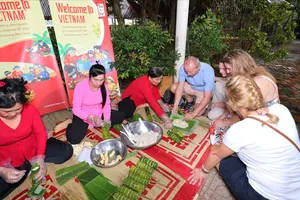 Du khách Ba Lan trải nghiệm gói bánh tét tại Đồng Tháp, chiều 5-2. Ảnh: BẢO THU