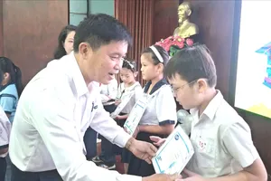 Ông Phan Công Trực, Giám đốc Tổ chức tài chính vi mô CEP, chi nhánh Tân Thới Hiệp, trao học bổng cho con công nhân. Ảnh: HỒNG ĐÀO