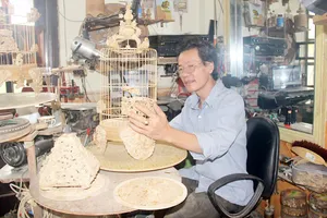 Nghệ nhân Đoàn Minh Căn bên chiếc lồng chim bằng tre tinh xảo