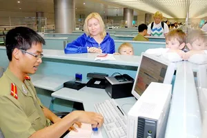 Sĩ quan an ninh cửa khẩu sân bay Tân Sơn Nhất làm thủ tục xuất nhập cảnh cho hành khách. Ảnh: CAO THĂNG