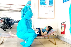 2 bác sĩ khám thai một cư dân trong khu vực phong tỏa. Ảnh: KHÁNH HƯNG