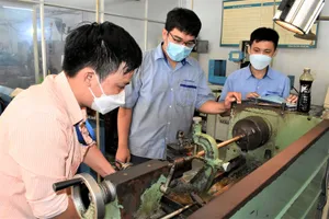 Thầy Lê Ngọc Tín (trái) hướng dẫn sinh viên năm cuối ngành Cắt gọt kim loại 1 thực hành trên máy