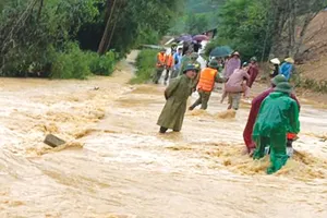 Lực lượng chức năng xã Hương Xuân, tỉnh Hà Tĩnh hỗ trợ người dân qua các cầu tràn nước chảy xiết. Ảnh: DƯƠNG QUANG