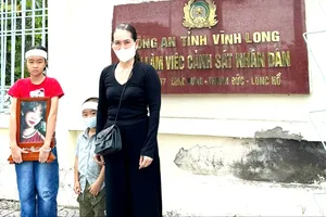 Bà Hiền cùng 2 con nhỏ và di ảnh bé Bảo Tr., trước Công an tỉnh Vĩnh Long