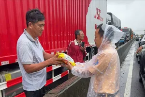 Lực lượng CSGT tiếp tế thực phẩm cho các tài xế có phương tiện bị kẹt trên quốc lộ 1A