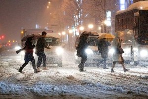 Pedestrians cross the street in the snow, in front of JR Yotsuya Station, in Tokyo, on Monday. - KYODO