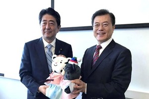 The file photo, taken Sept. 7, 2017, shows South Korean President Moon Jae-in (R) offering the mascots of the 2018 PyeongChang Winter Olympic Games to Japanese Prime Minister Shinzo Abe before the start of their bilateral summit on the sidelines of a regi