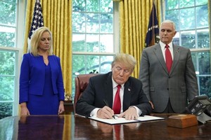 US President Donald Trump -- flanked by Homeland Security Secretary Kirstjen Nielsen (left) and Vice President Mike Pence -- signs an executive order to end family separations at the border.—AFP/VNA Photo
