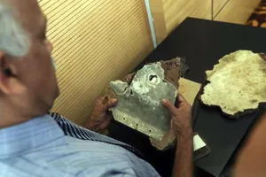 Một quan chức Malaysia kiểm tra các mảnh vỡ được cho là từ máy bay MH370 trong cuộc họp báo tại trụ sở Bộ Giao thông Malaysia ở Putrajaya ngày 30-11-2018. Ảnh: EPA-EFE