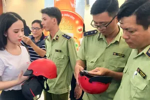 Cán bộ QLTT hướng dẫn phân biệt nón bảo hiểm thật - giả tại một sự kiện vừa diễn ra ở TPHCM. Ảnh: THI HỒNG