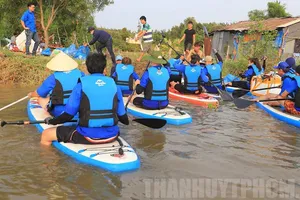 Dùng ván chèo vớt rác và tuyên truyền bảo vệ môi trường