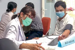 Nhân viên y tế đo huyết áp cho người dân trước khi tiêm vaccine phòng Covid-19
