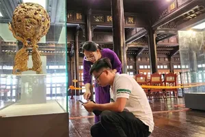 Du khách sử dụng smartphone tương tác với chip NFC gắn trên cổ vật trưng bày tại Bảo tàng Cổ vật Cung đình Huế