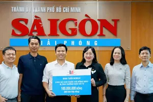 Phó Tổng biên tập Báo Sài Gòn Giải Phóng Bùi Thị Hồng Sương tiếp nhận bảng tặng 100 triệu đồng chia sẻ khó khăn với đồng bào bị ảnh hưởng bão số 10 từ ông Nguyễn Minh Tuấn, Giám đốc hệ thống Minh Tuấn Mobile (áo trắng giữa) . Ảnh: VIỆT NGA 