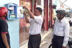 Cán bộ Hội Chữ thập đỏ hướng dẫn cho người dân  xung quanh sử dụng tủ thuốc sơ cấp cứu.