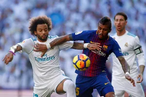 Marcelo (trái, Real Madrid) tranh bóng với Paulinho (Barcelona)