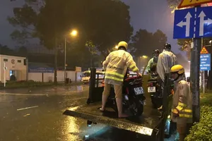 Hình ảnh CSGT giúp dân đưa xe vượt điểm ngập trong cơn bão số 9 ở trung tâm TPHCM. Ảnh: ĐAN NGUYÊN