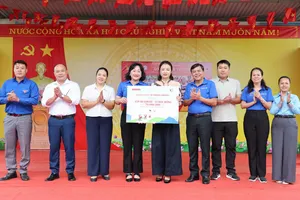 Đồng chí Tăng Hữu Phong, Phó Trưởng Ban Tuyên giáo Thành ủy TPHCM cùng Phó Tổng Biên tập Báo SGGP Bùi Thị Hồng Sương và lãnh đạo lãnh đạo xã Tràng Định tặng bảng biểu trưng áo ấm và học bổng cho lãnh đạo nhà trường. Ảnh: QUANG PHÚC