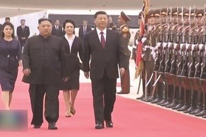 金正恩（左）和習近平在機場檢閱朝鮮人民軍儀仗隊。