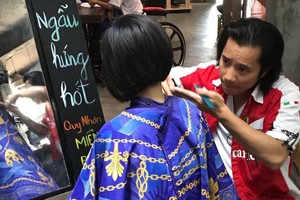 黎俊在歸仁市為某兒童輔助中心的女孩免費理髮。