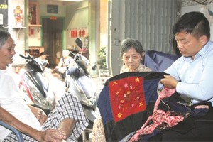 黃達銘老夫婦向麒麟（右一）贈送距今70多年其母親用於背著弟妹來越的“咩帶”。