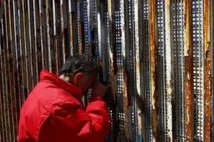 墨西哥提華納，移民家庭隔著美墨邊境之間的隔離牆聊天。（圖源：互聯網） 