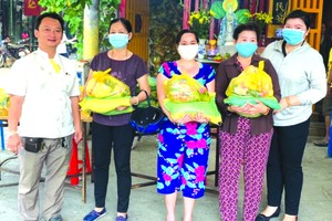 　　富山五行廟慈善組組長鄒國榮(左一)與 第十五坊祖國陣線委員會主席黃氏青美川 (右一)向貧困者派發賑濟品。